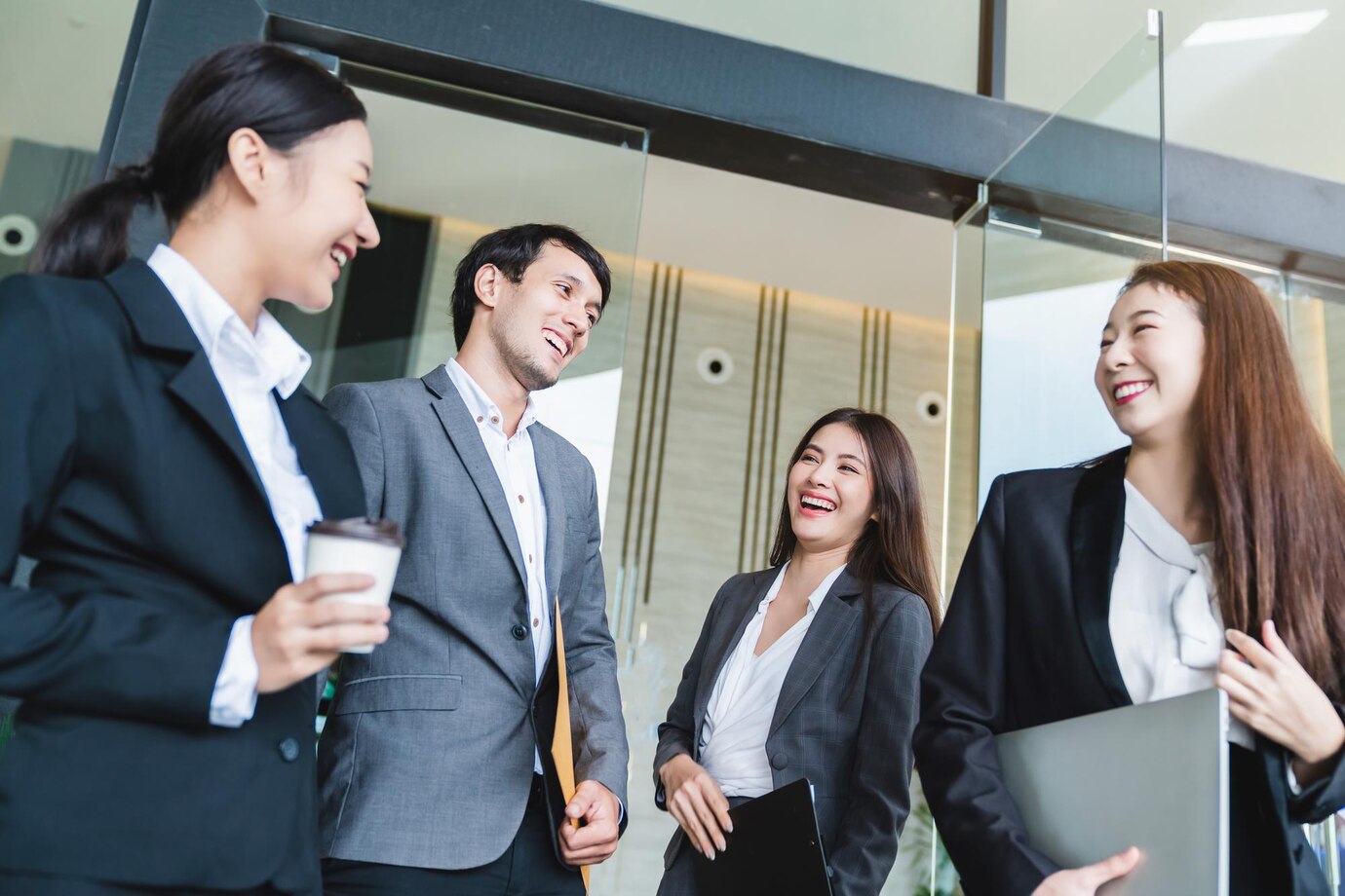 Group of smart young asian businessmale and female formal dress walking pass modern office entrance with confident and happiness
