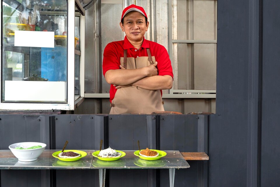 Asian man with a hat and apron cooking serabi