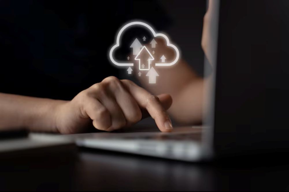 Woman using laptop for upload with cloud icon hologram effect