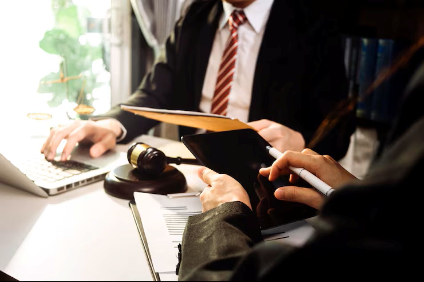 Business and lawyers discussing contract papers with brass scale on desk