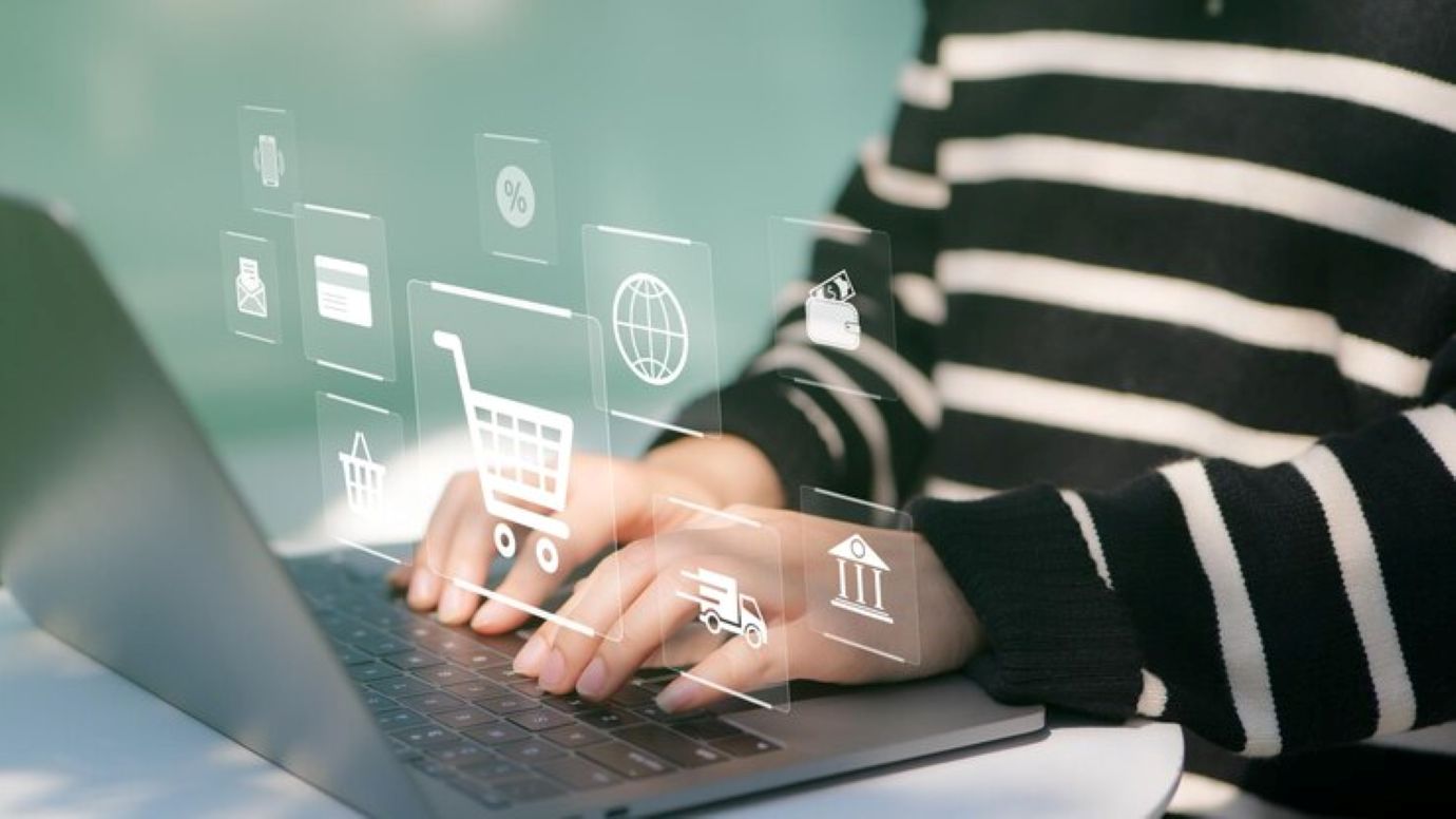 Woman or shopper using a laptop computer with shopping cart